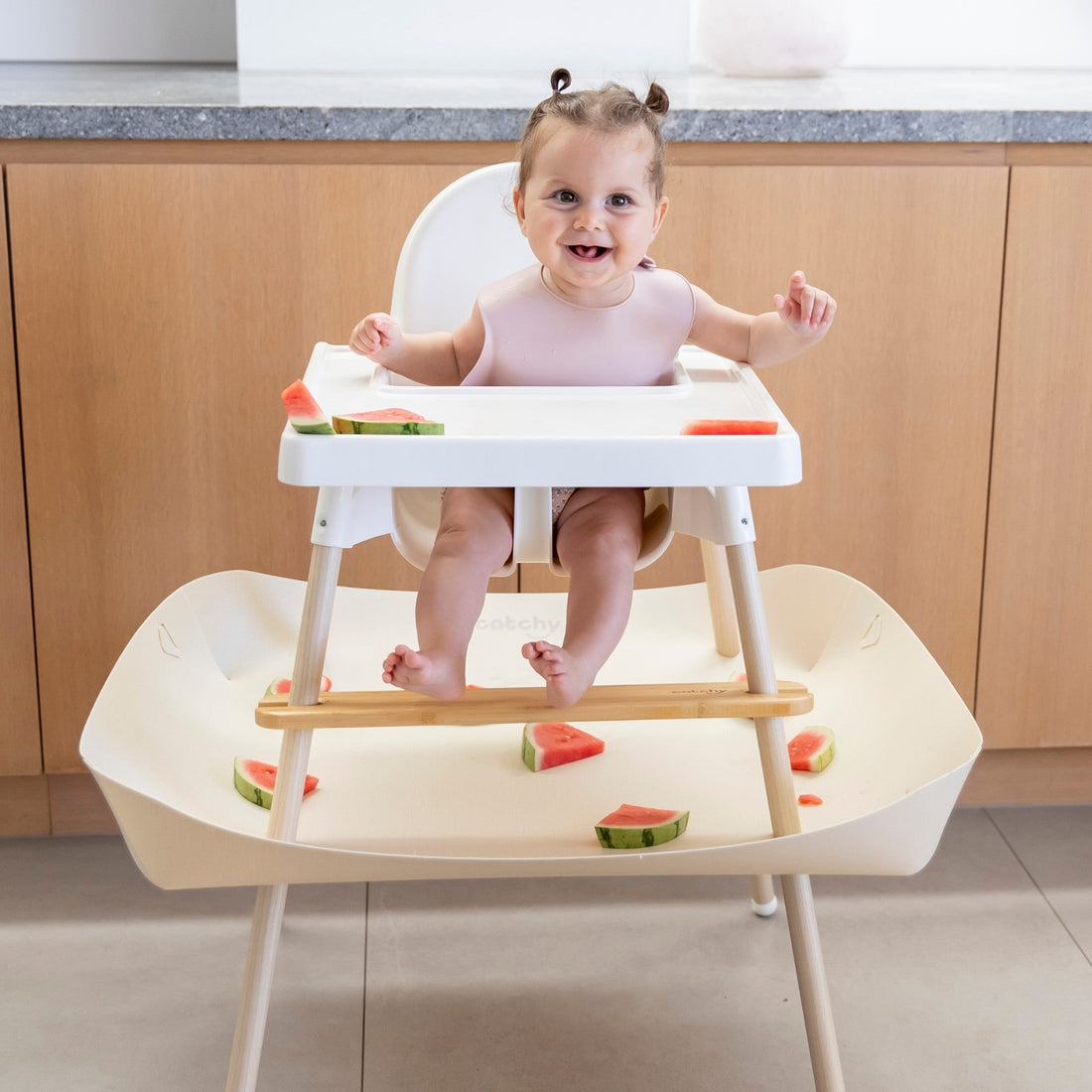 Baby eating watermelon in high chair with mess-catching tray, food-safe and easy clean design
