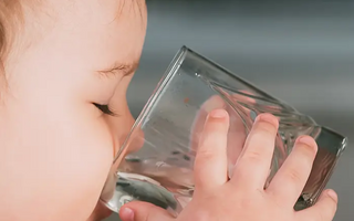 Baby drinking water from clear glass, mess-free mealtime solution for parents