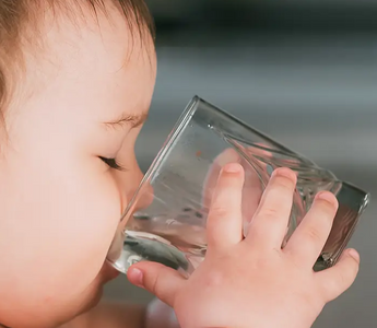 Baby drinking water from clear glass, mess-free mealtime solution for parents