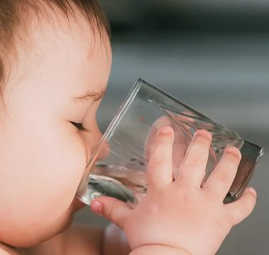 Baby drinking water from clear glass, mess-free mealtime solution for parents