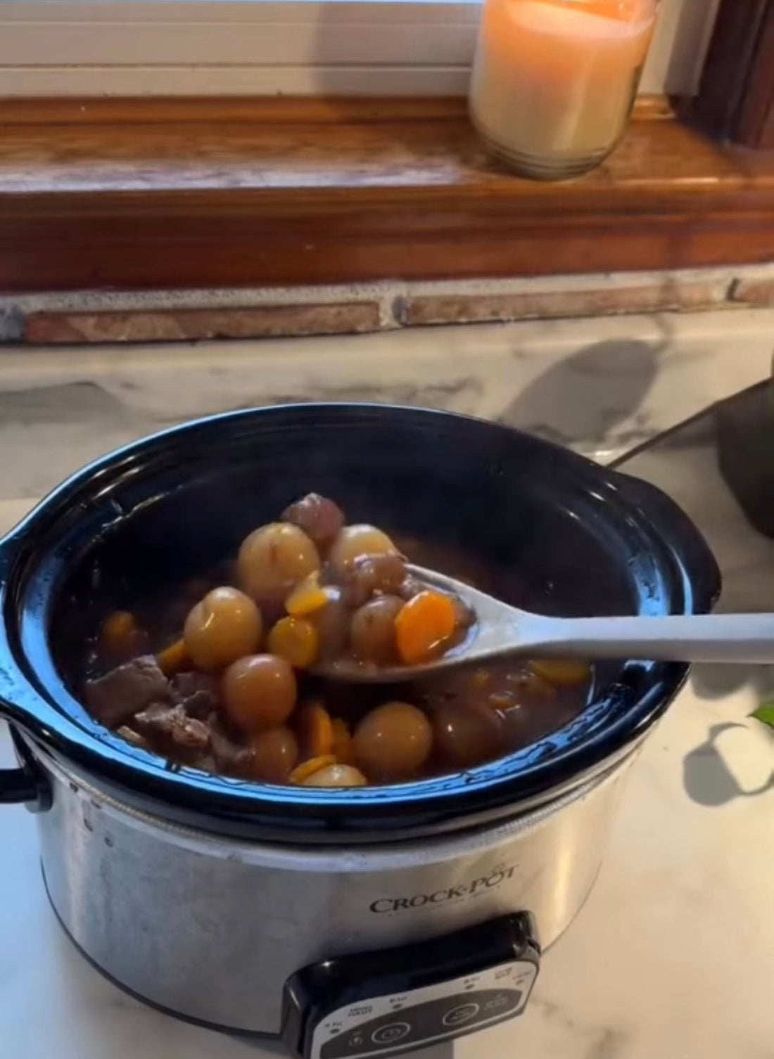 Crock-Pot slow cooker with hearty stew, carrots, and potatoes on kitchen counter