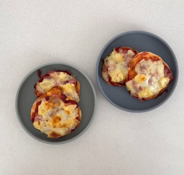 Two gray plates with mini cheesy pizzas on a clean countertop, perfect for mess-free meals.