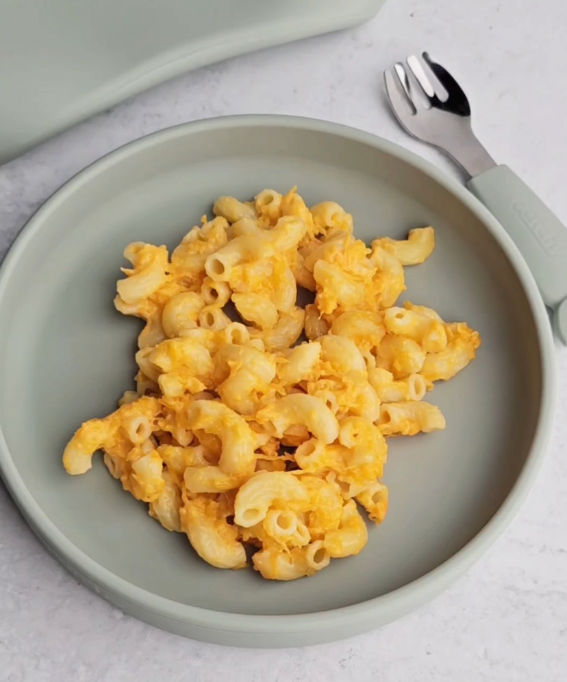 Mac and cheese on a sage green silicone plate with matching fork, mess-free meal solution