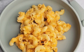 Mac and cheese on a sage green silicone plate with matching fork, mess-free meal solution