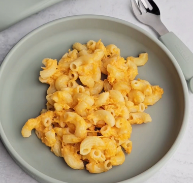 Mac and cheese on a sage green silicone plate with matching fork, mess-free meal solution