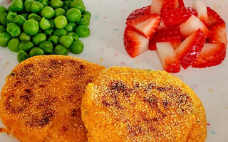 Kid-friendly meal with crispy patties, peas, and strawberries on colorful plate