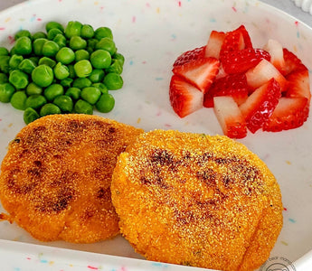 Kid-friendly meal with crispy patties, peas, and strawberries on colorful plate
